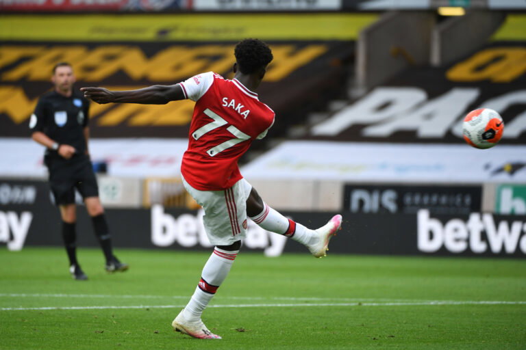 WOLVERHAMPTON, ENGLAND - JULY 04: Bukayo Saka of Arsenal scores a goal to make it 0-1 during the Premier League match between Wolverhampton Wanderers and Arsenal FC at Molineux on July 4, 2020 in Wolverhampton, United Kingdom. Football Stadiums around Europe remain empty due to the Coronavirus Pandemic as Government social distancing laws prohibit fans inside venues resulting in all fixtures being played behind closed doors. (Photo by Sam Bagnall - AMA/Getty Images)